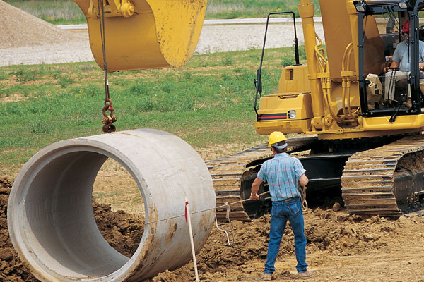 Cat Excavator Lowering Sewer in the Ground